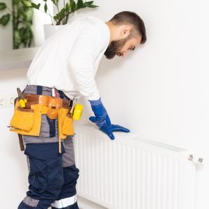 man repairing radiator with wrench. Removing air from the radiator.